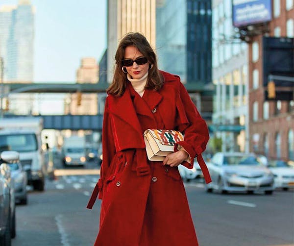 A woman in a red coat is walking down the street