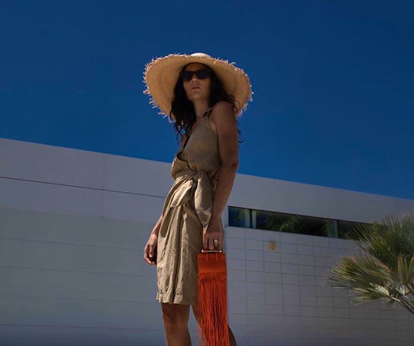 A woman in a hat and dress standing on a beach