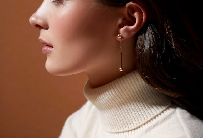 A woman wearing a white sweater and gold earrings
