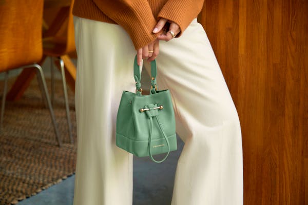 Una donna che tiene una borsa verde nella mano destra