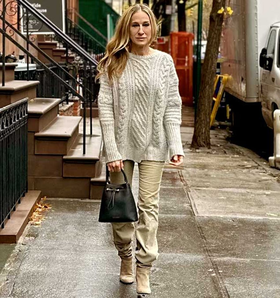 A woman is walking down the street with a handbag