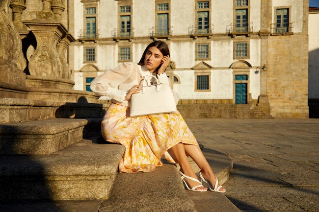 A woman sitting on a ledge with a handbag