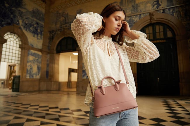 A woman holding a pink purse in a building