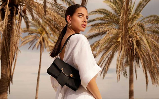 A woman in a white dress carrying a black purse