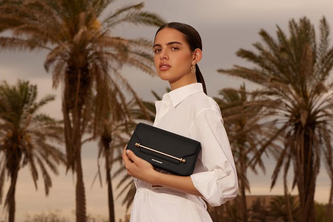 A woman in a white shirt holding a black purse