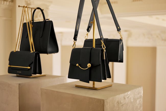 A pair of black purses hanging from a metal holder