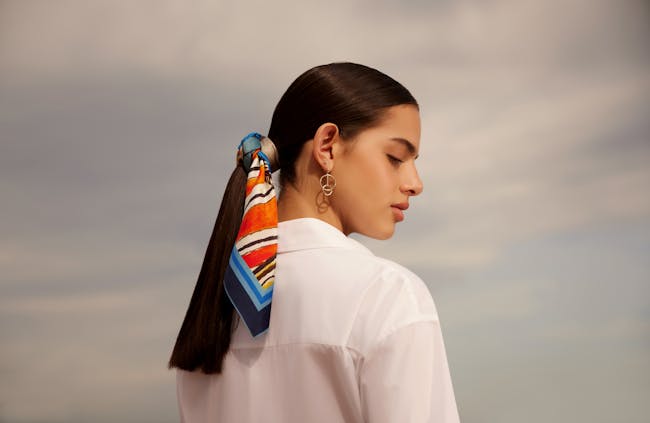 A woman with a pony tail with a colorful scarf around her neck