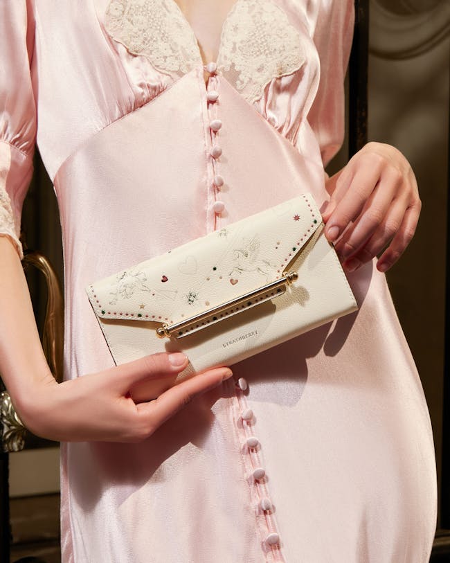 A woman in a pink dress holding a white purse