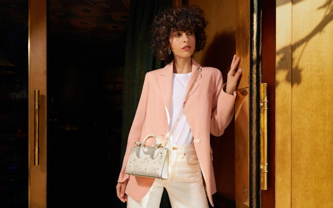 A woman standing in a doorway with a handbag