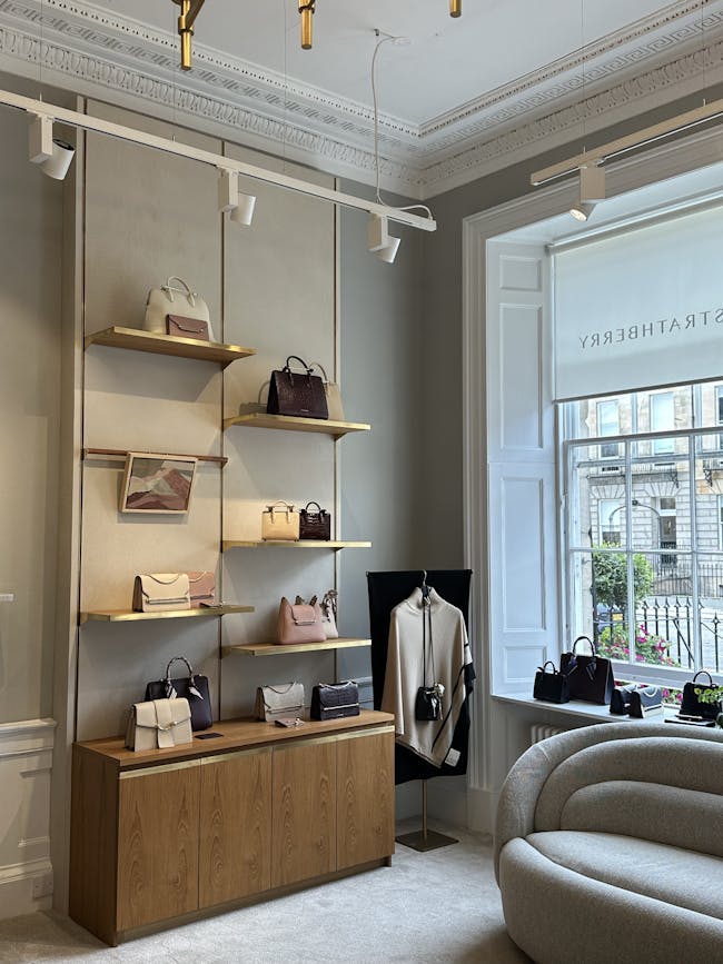 A room with a couch and a shelf with purses on it