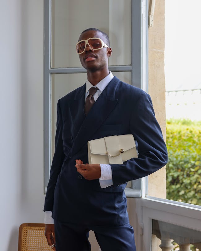 A man in a suit and sunglasses holding a purse