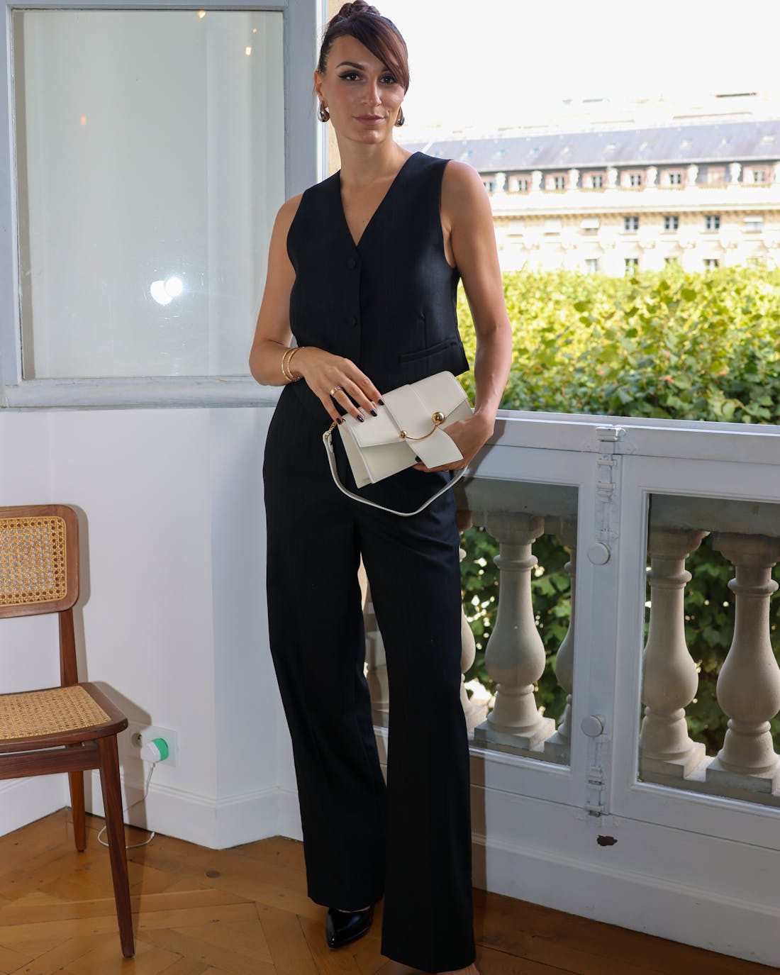 A woman in a black jumpsuit holding a white purse