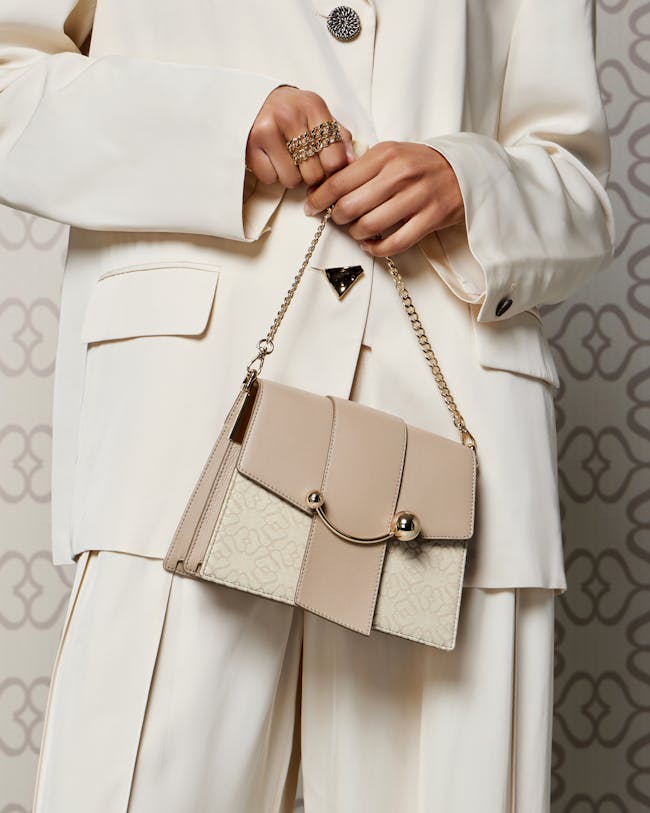 A woman in a white suit holding a beige purse