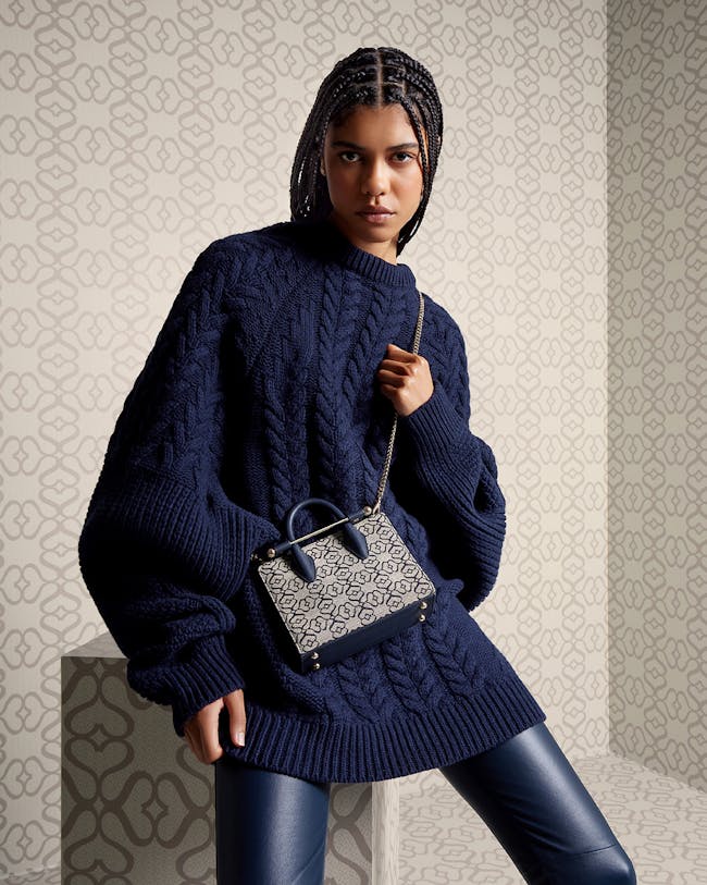 A woman in a blue sweater holding a purse