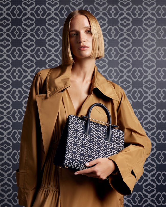 A woman in a trench coat holding a handbag