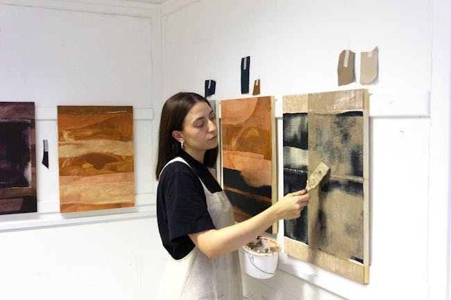 A woman in an apron painting on a wall