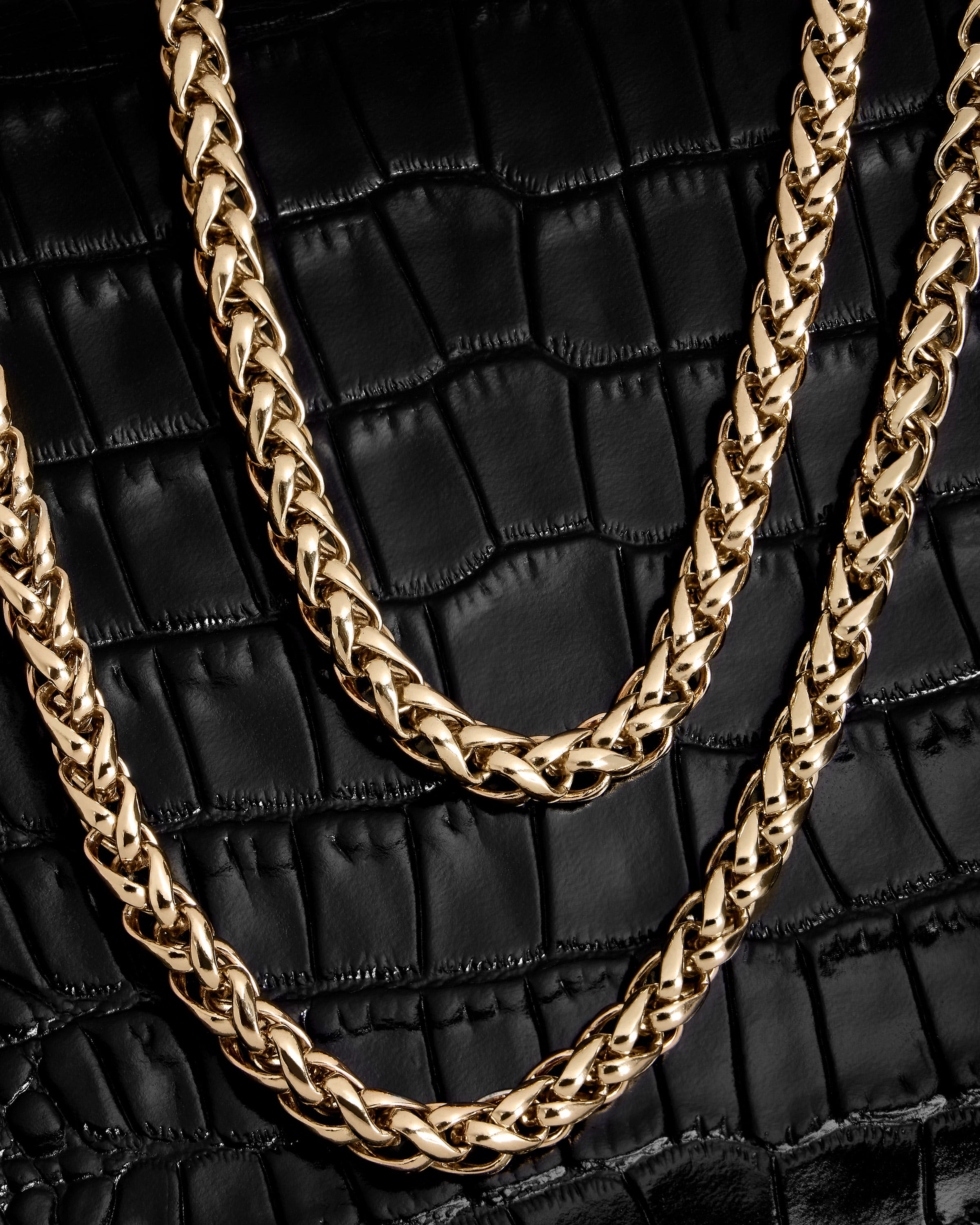 A close up of a gold chain on a black purse