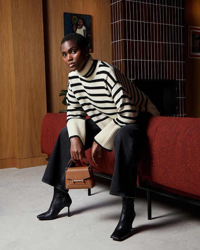 A woman sitting on a bed holding a purse
