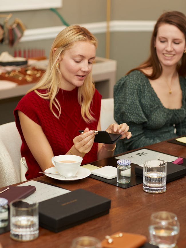 Two women sitting at a table looking at a cell phone