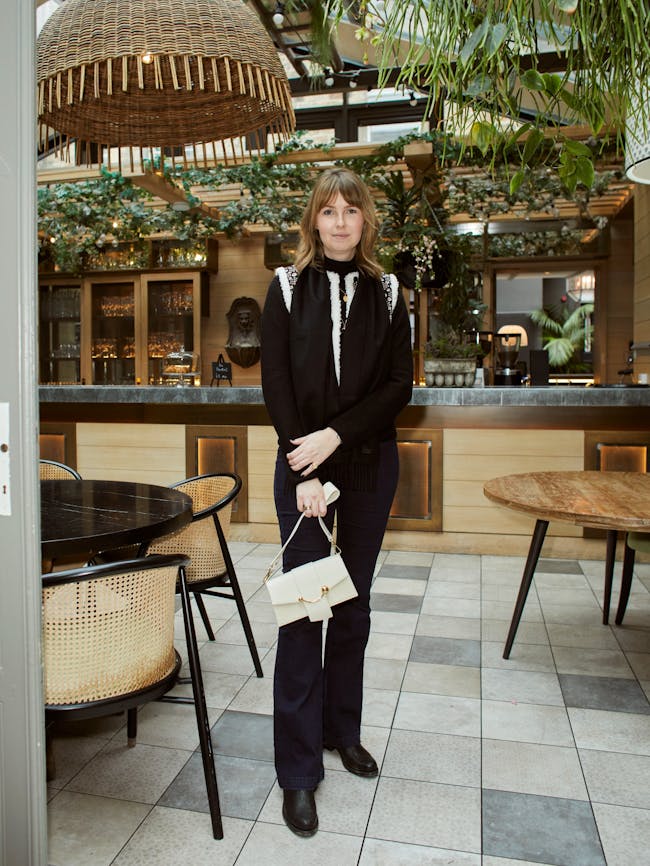 A woman standing in a restaurant holding a purse