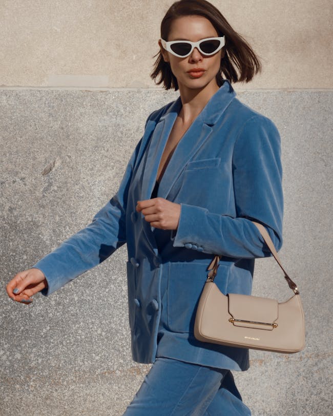 A woman in a blue suit carrying a beige purse