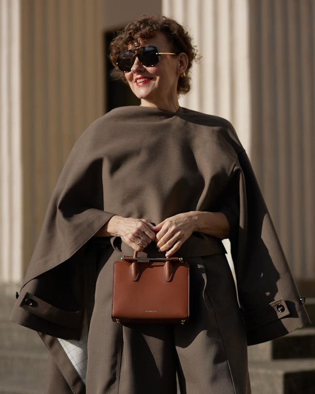 A woman in a brown cape carrying a brown purse