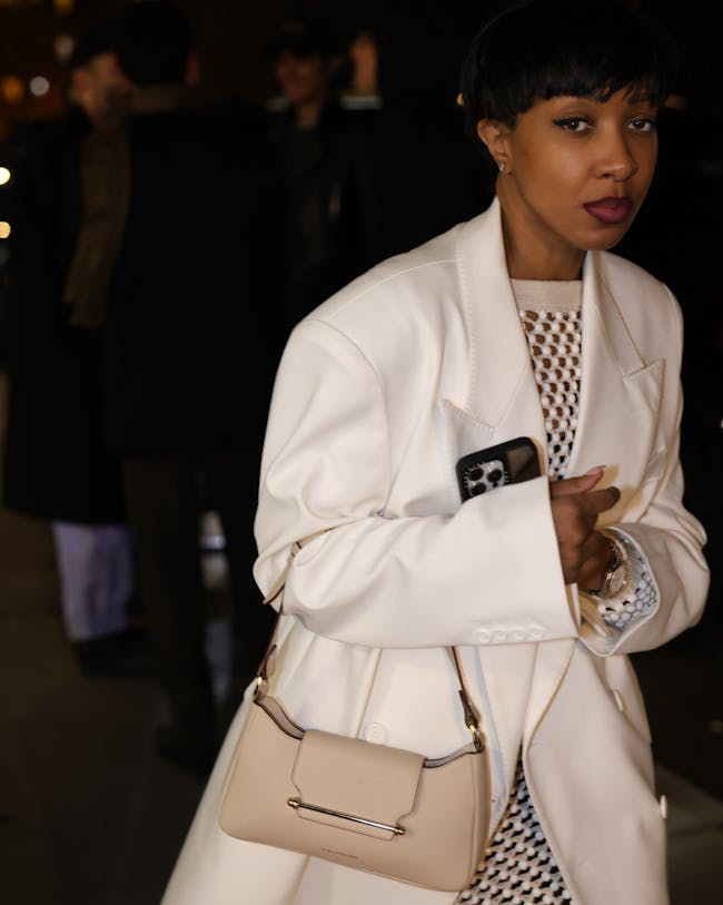 A woman in a white coat carrying a beige purse