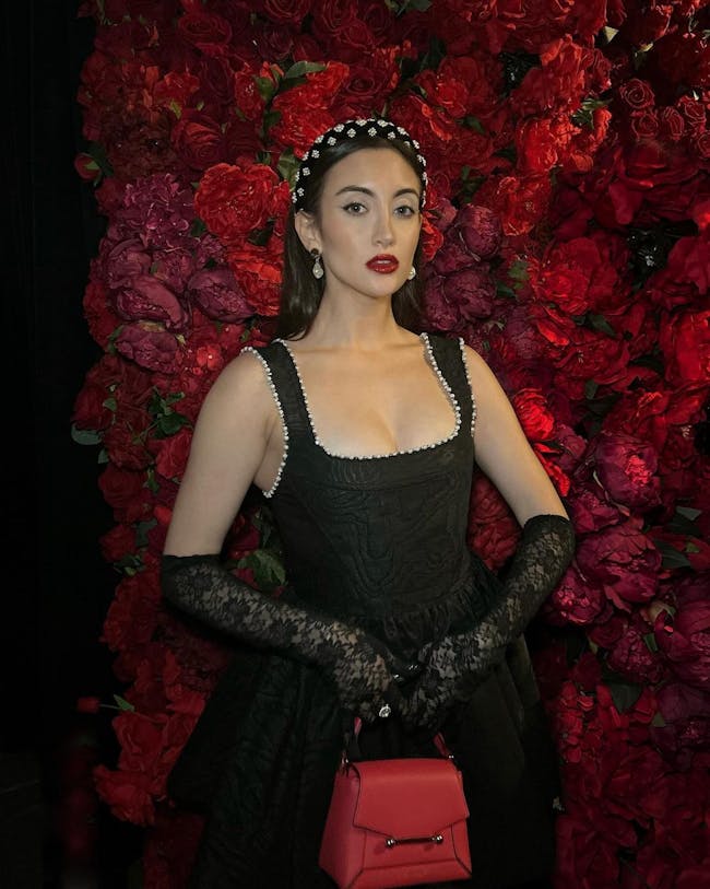 A woman in a black dress holding a red purse