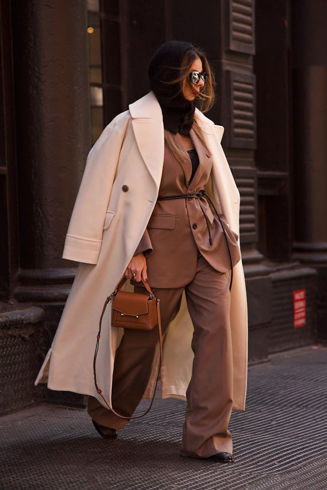 A woman is walking down the street in a trench coat
