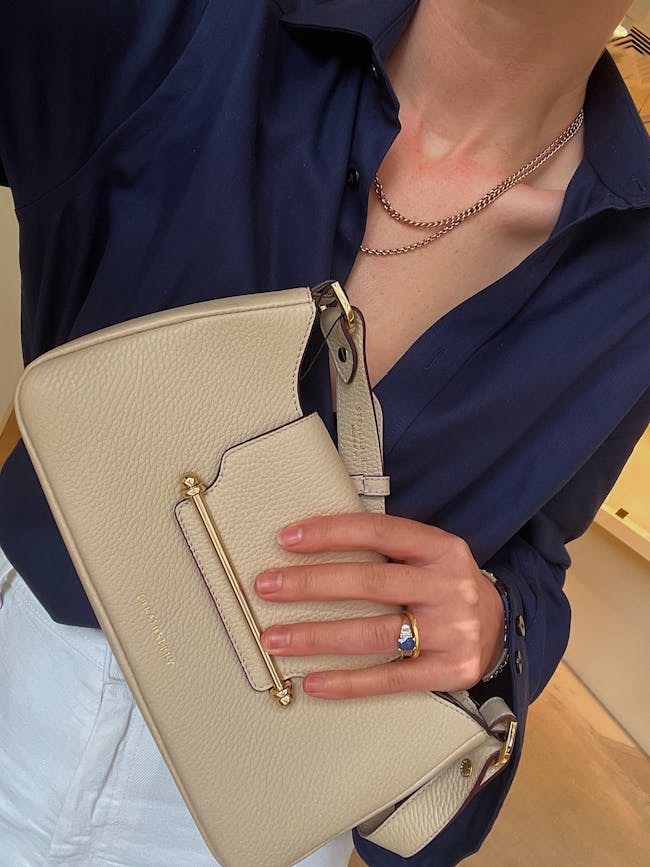 A woman wearing a blue shirt holding a white purse