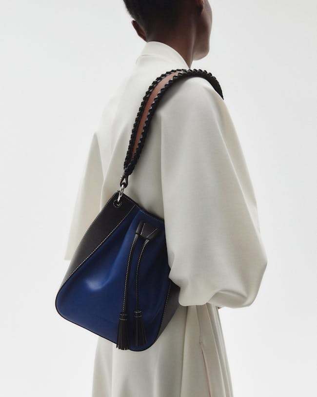 A woman in a white dress carrying a blue handbag
