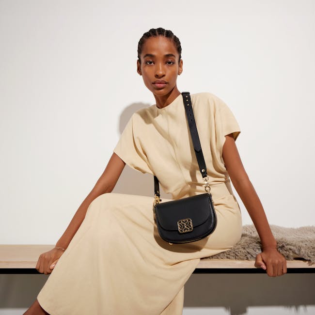 A woman sitting on a bench holding a black purse