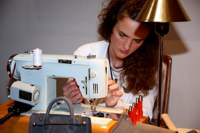 One of our atelier workers, at an event in Edinburgh in partnership with Hamilton and Inches. Showing the detailed work that goes into crafting our handbags, as she aligns the sewing machine to finish the stitching on a swatch of leather.