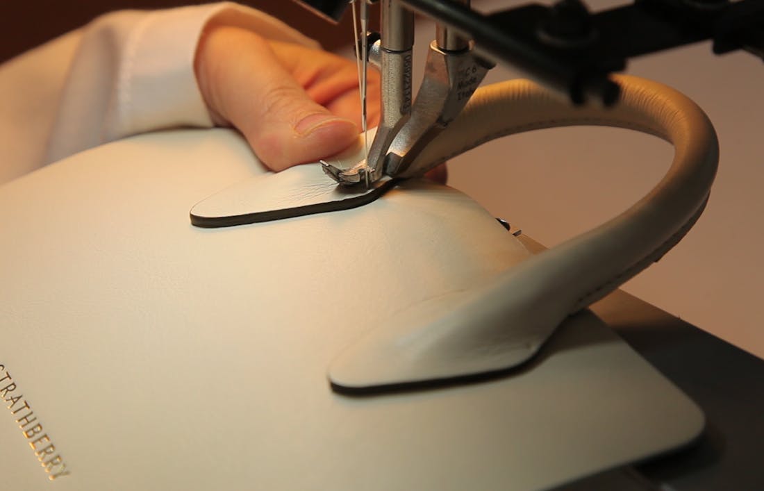 A detailed shot of the construction of a Strathberry handbag. Focusing on the stitching around the leather top handle of a tote handbag, shown in the atelier in Ubrique, Spain.