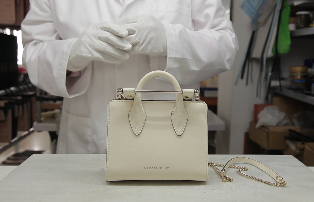 A Strathberry Nano Tote handbag shown in the atelier workroom in Ubrique, Spain. The handbag is shown in vanilla, with the atelier craftsman having completed the process of putting the bag together for final display.