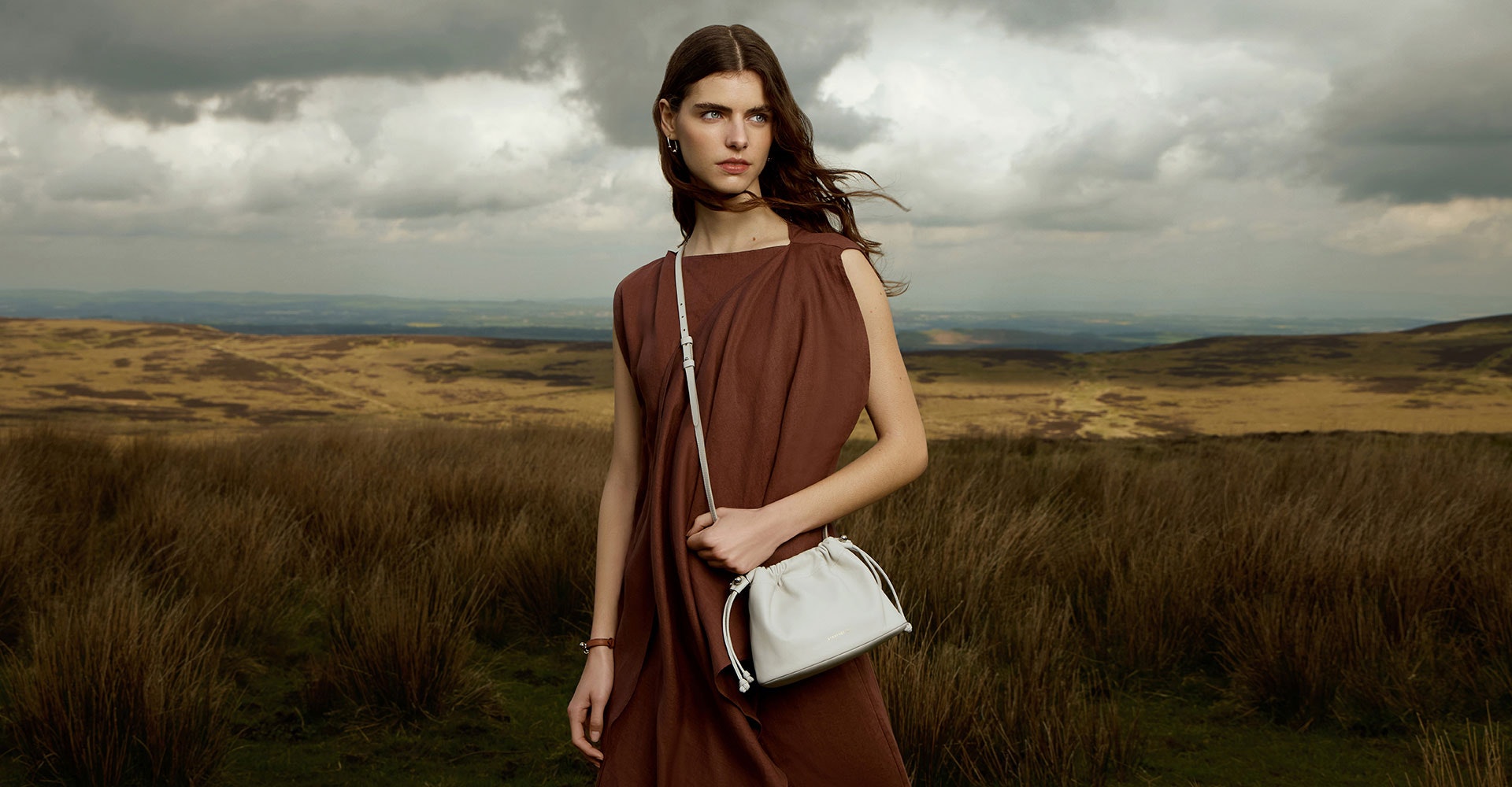 A woman in a brown dress holding a white purse