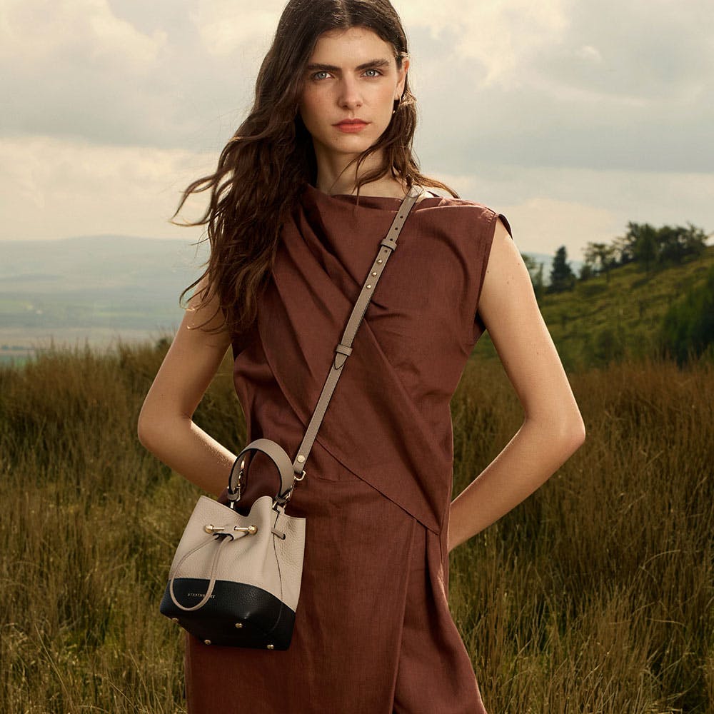 A woman in a brown dress holding a purse