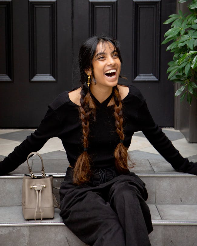 A woman sitting on the steps laughing and holding a purse