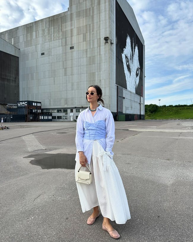 A woman standing in a parking lot with a building in the background