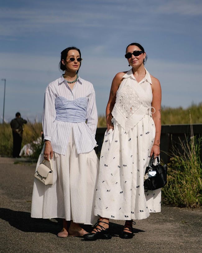 Two women standing next to each other on a road