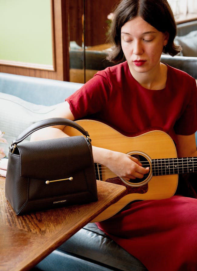 A woman sitting on a couch playing a guitar