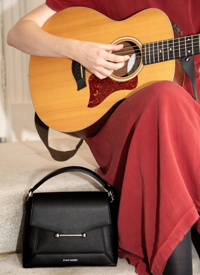 A woman sitting on a couch playing a guitar