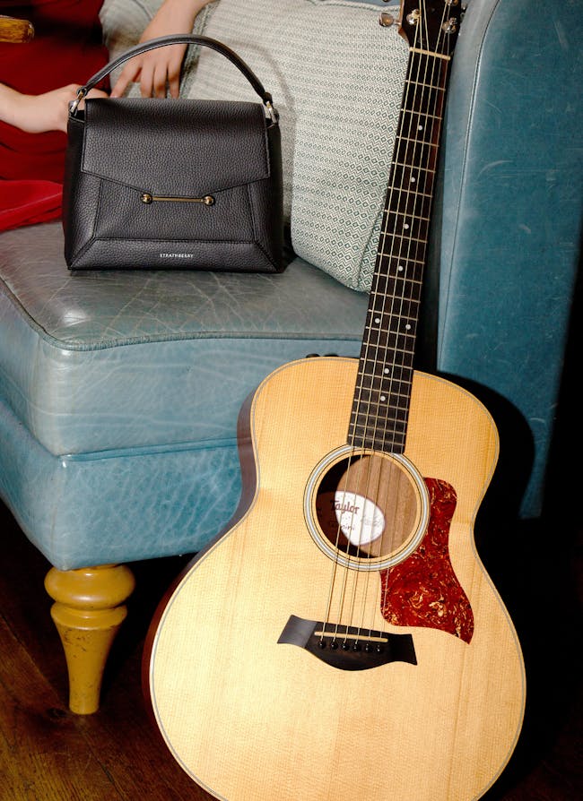 A woman sitting on a couch next to a guitar