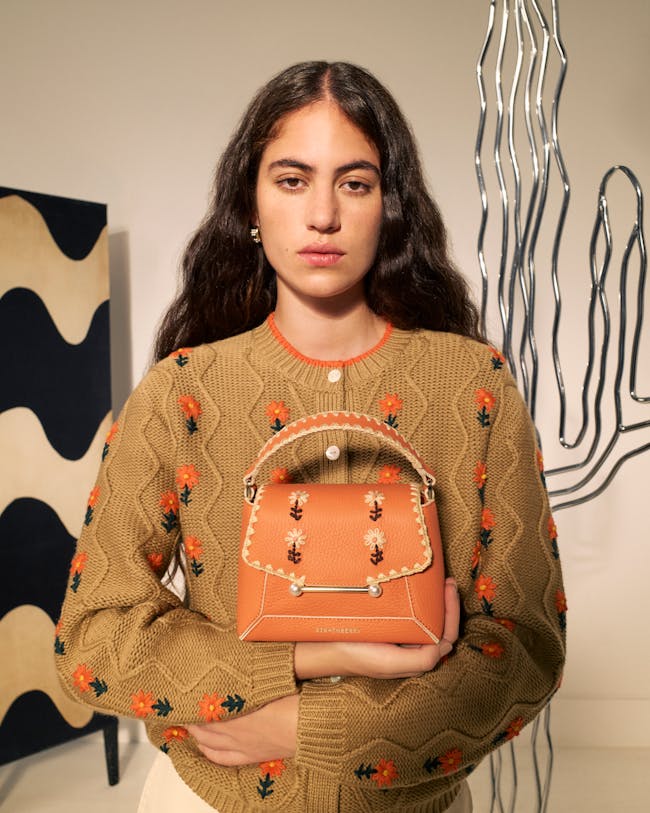 A woman holding a small purse in her hands