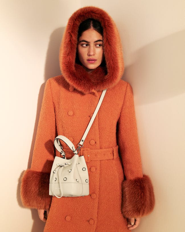 A woman in an orange coat with a white purse
