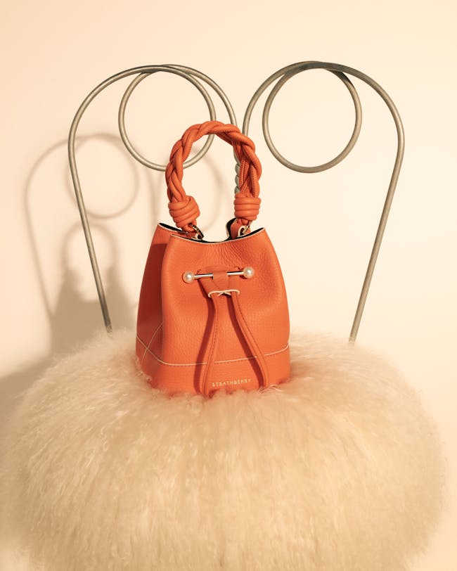 An orange purse sitting on top of a chair