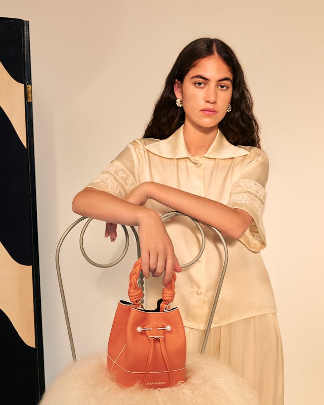 A woman in a white dress holding a brown purse