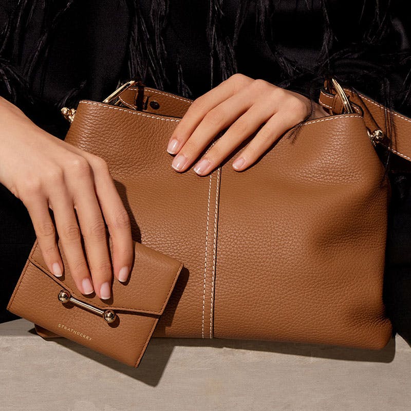 A woman's hand holding a brown purse