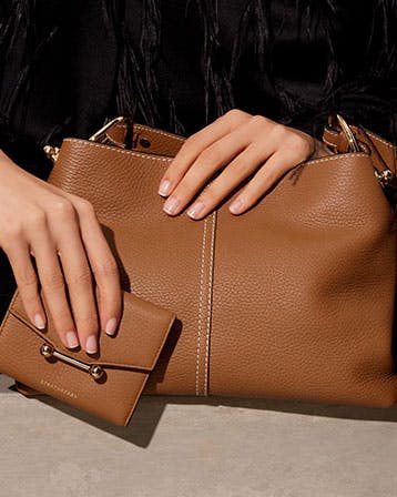 A woman's hand holding a brown purse