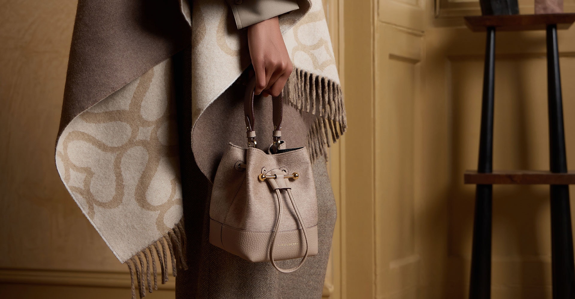 A woman's hand holding a beige purse